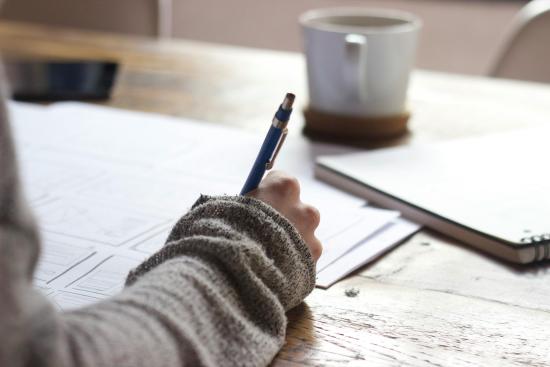 mano dereFoto por Unseen Studio en Unsplash.comcha escribiendo sobre papel