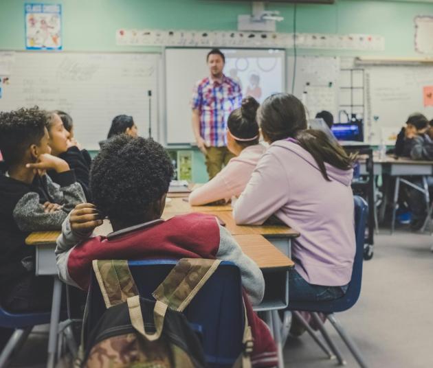 clase completa de alumnos sentados en pupitres y profesor delante