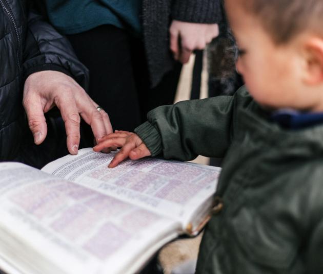 niño señalando letras en un libro abierto